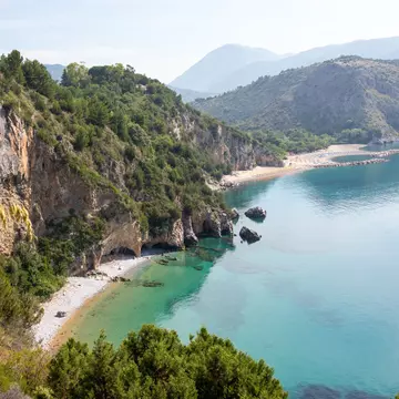 Mountainous landscape with white sandy beach and blue sea