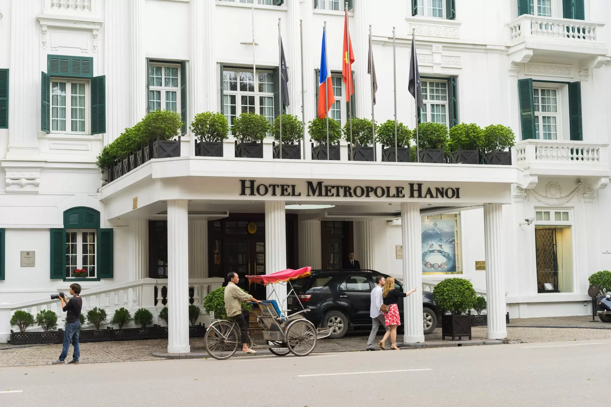 A cycle rickshaw passes the main entrance to the Sofitel Legend Metropole hotel in Hanoi, Vietnam.