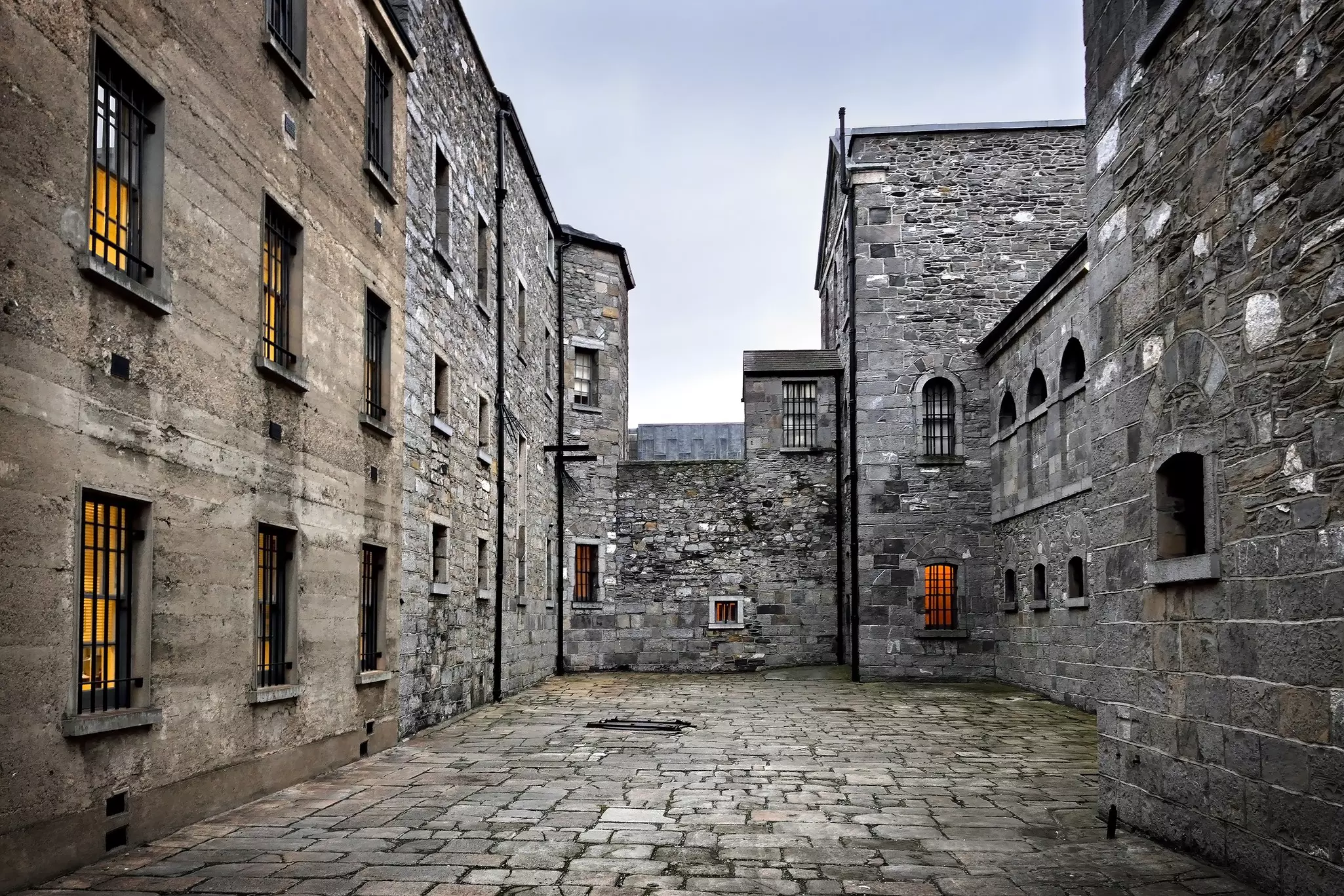 The stone-paved courtyard of old stone prison, surrounded by massive stone walls.