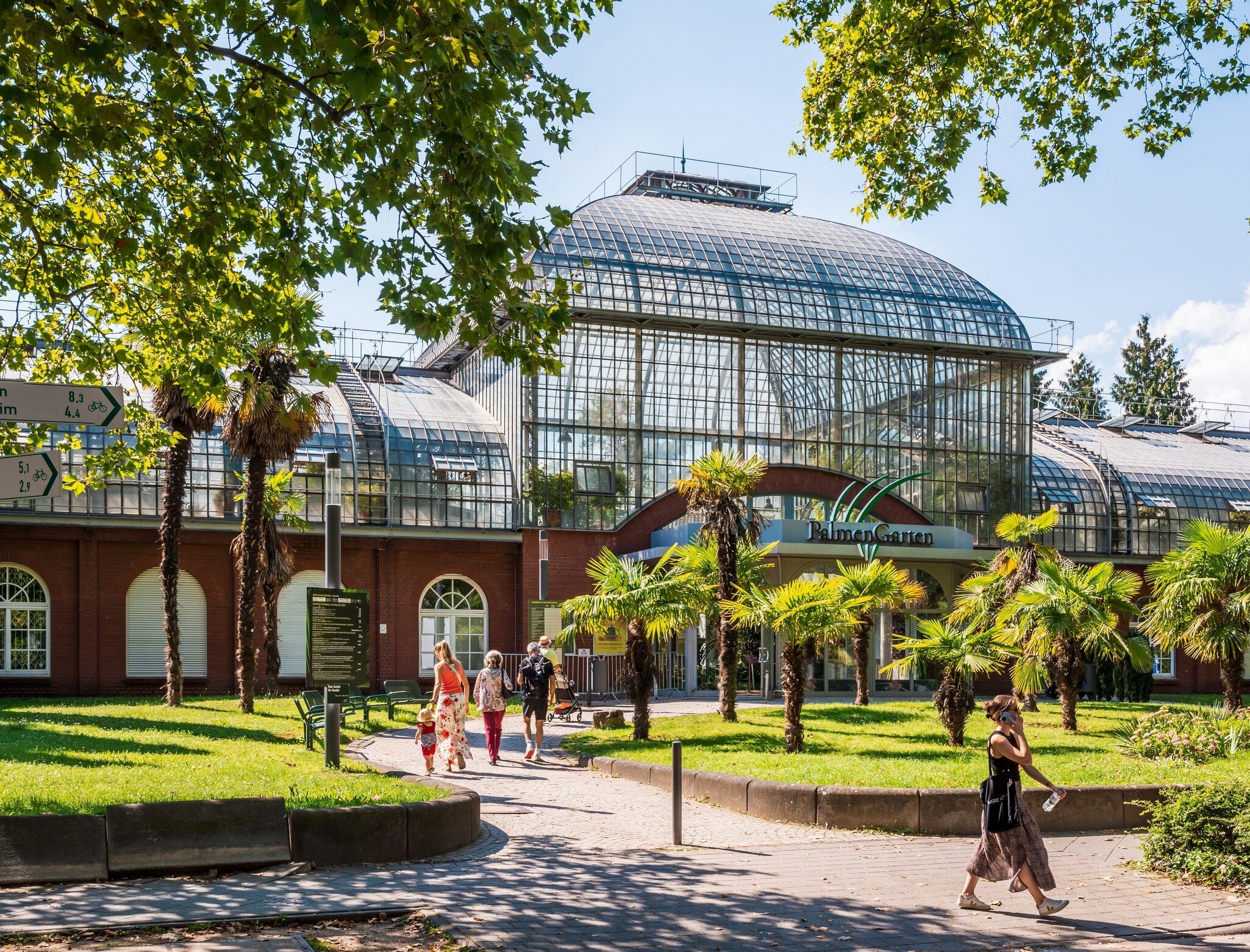 Tourists head toward the main entrance of the Palmengarten, one of three botanical gardens in Frankfurt, Germany.