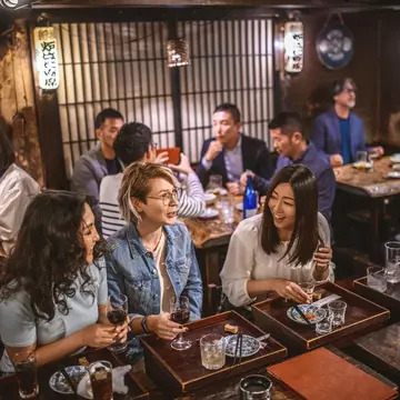 Wide angle view of Mongolian, Japanese, and Caucasian women sitting at sushi bar and other patrons in Tokyo izakaya.
1176105697