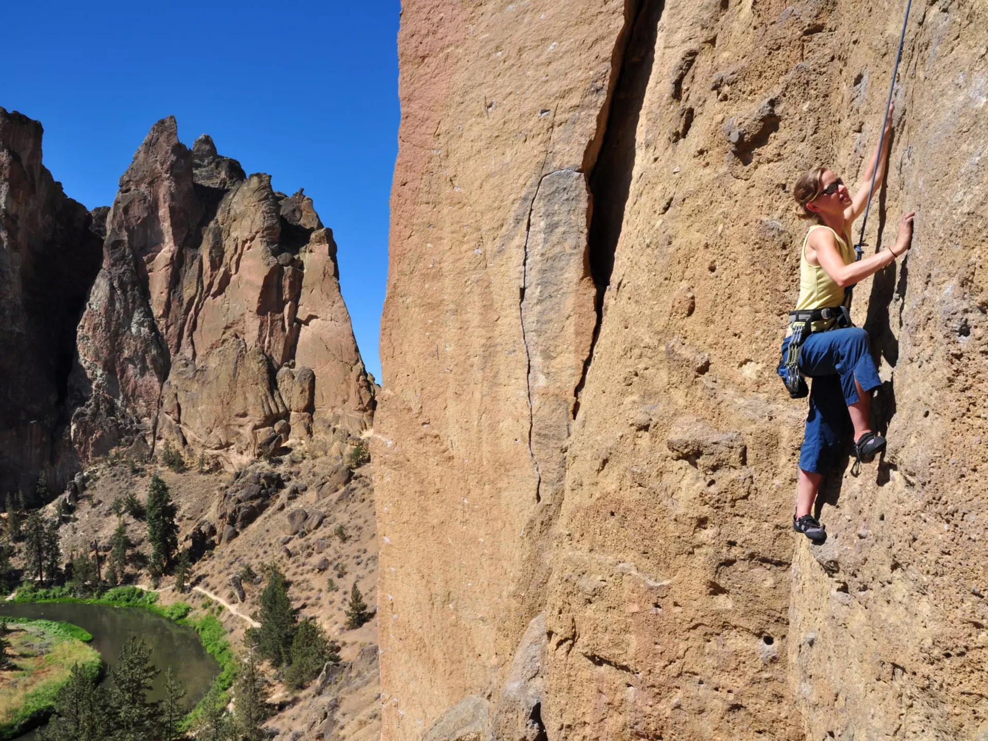 A woman ascends a cliff at Smith Rock State Park