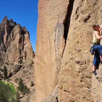 A woman ascends a cliff at Smith Rock State Park