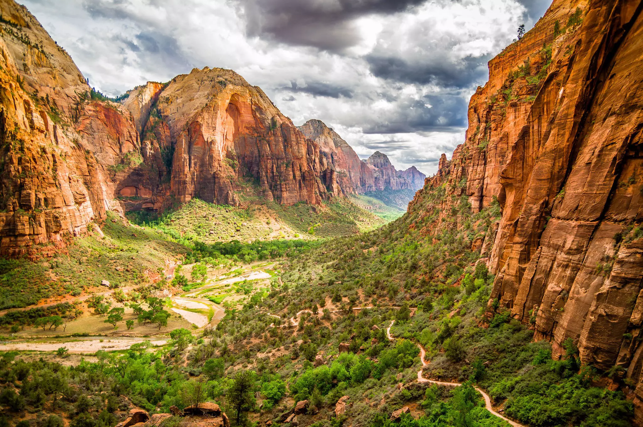A green valley cuts between two huge red-rock cliff faces