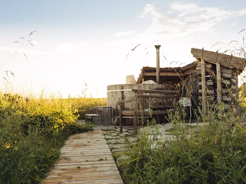 An outdoor fire-heated bath in a grassy field.