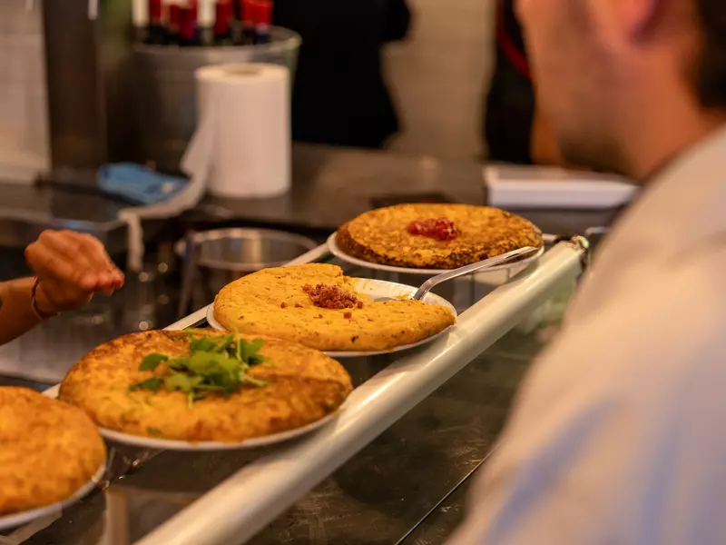 Tortilla de patatas lined up on a serving counter