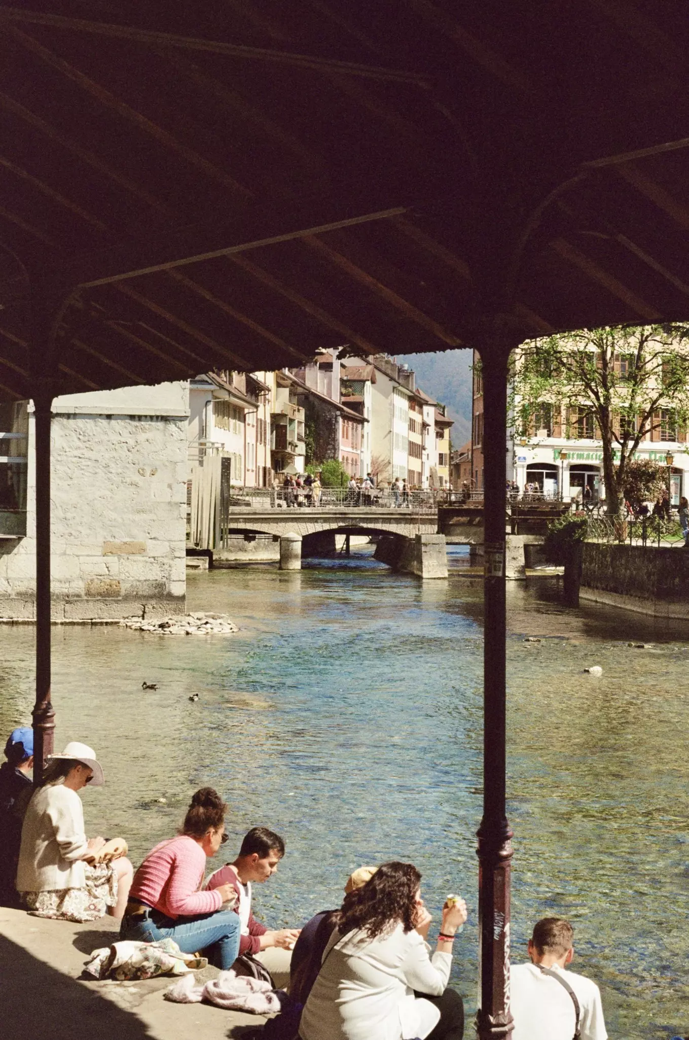 People stand on a bridge over a canal leading to a lake