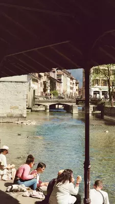 People stand on a bridge over a canal leading to a lake
