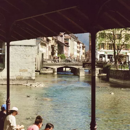 People sit by a canal in a town in France.