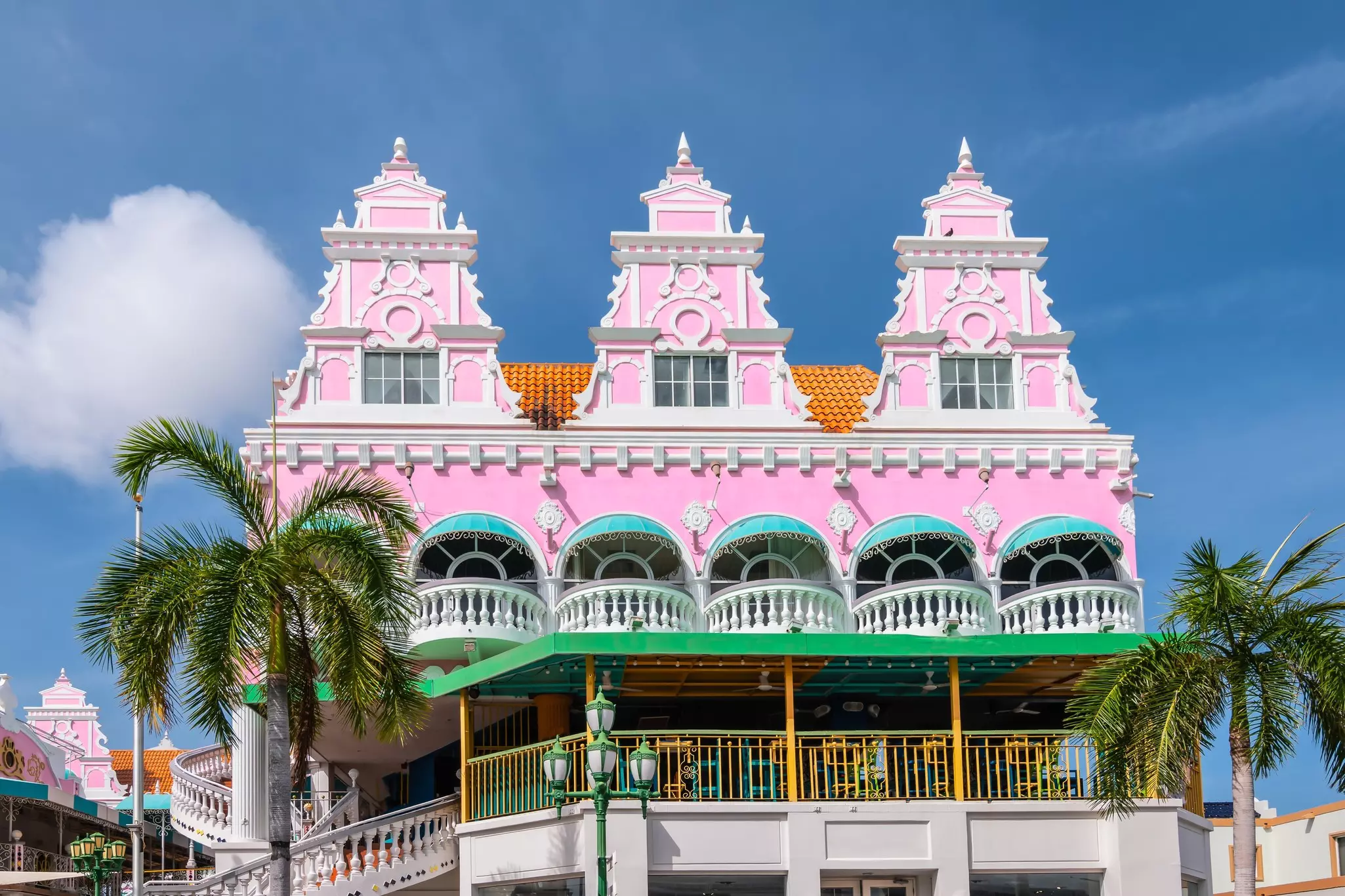 A pink building with decorative features and a large upper patio.