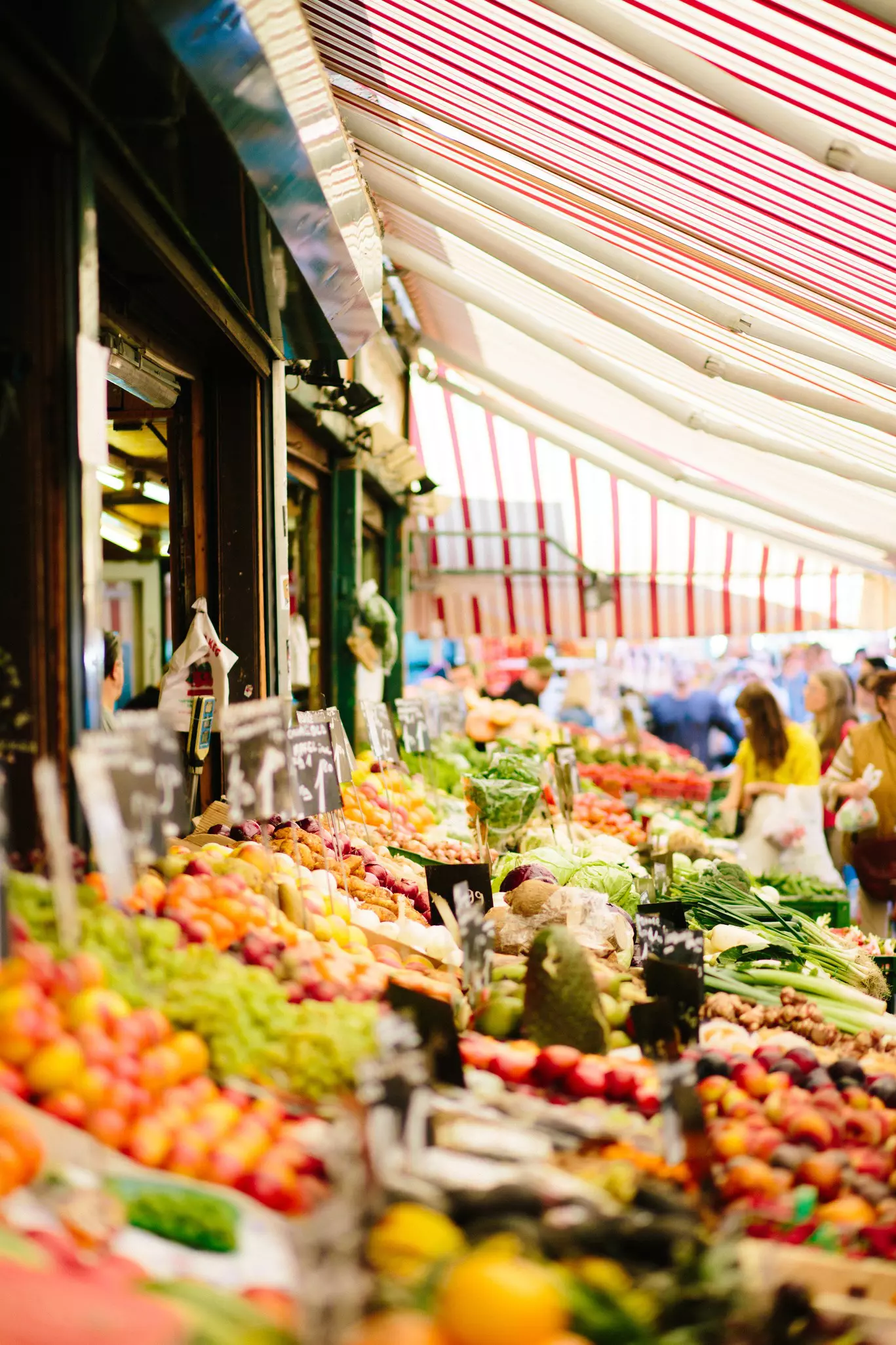 People shop among rows of fruit and veg for sale in a food market