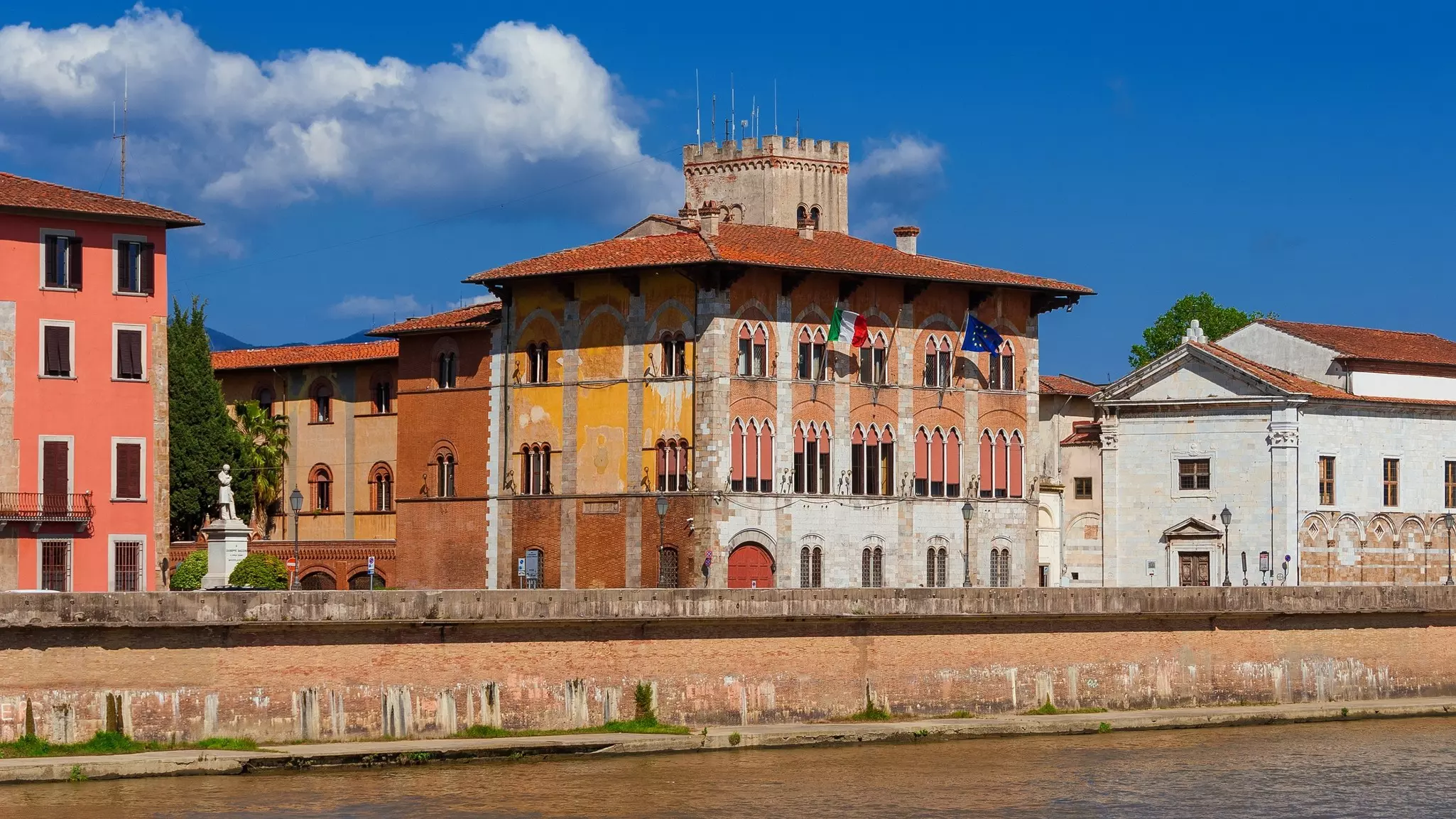Terracotta-colored buildings overlooking a river on a sunny day.
