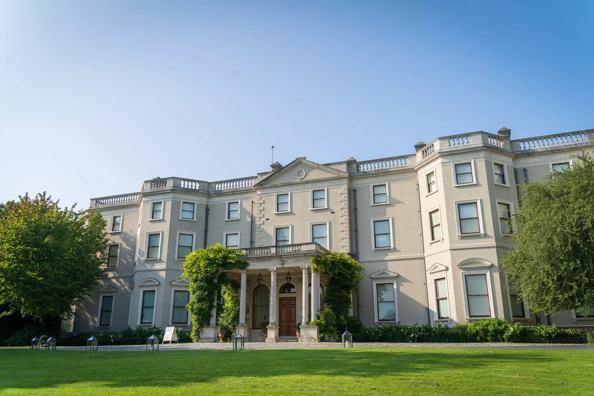 Wide view of large stone estate with grassy lawn in front.