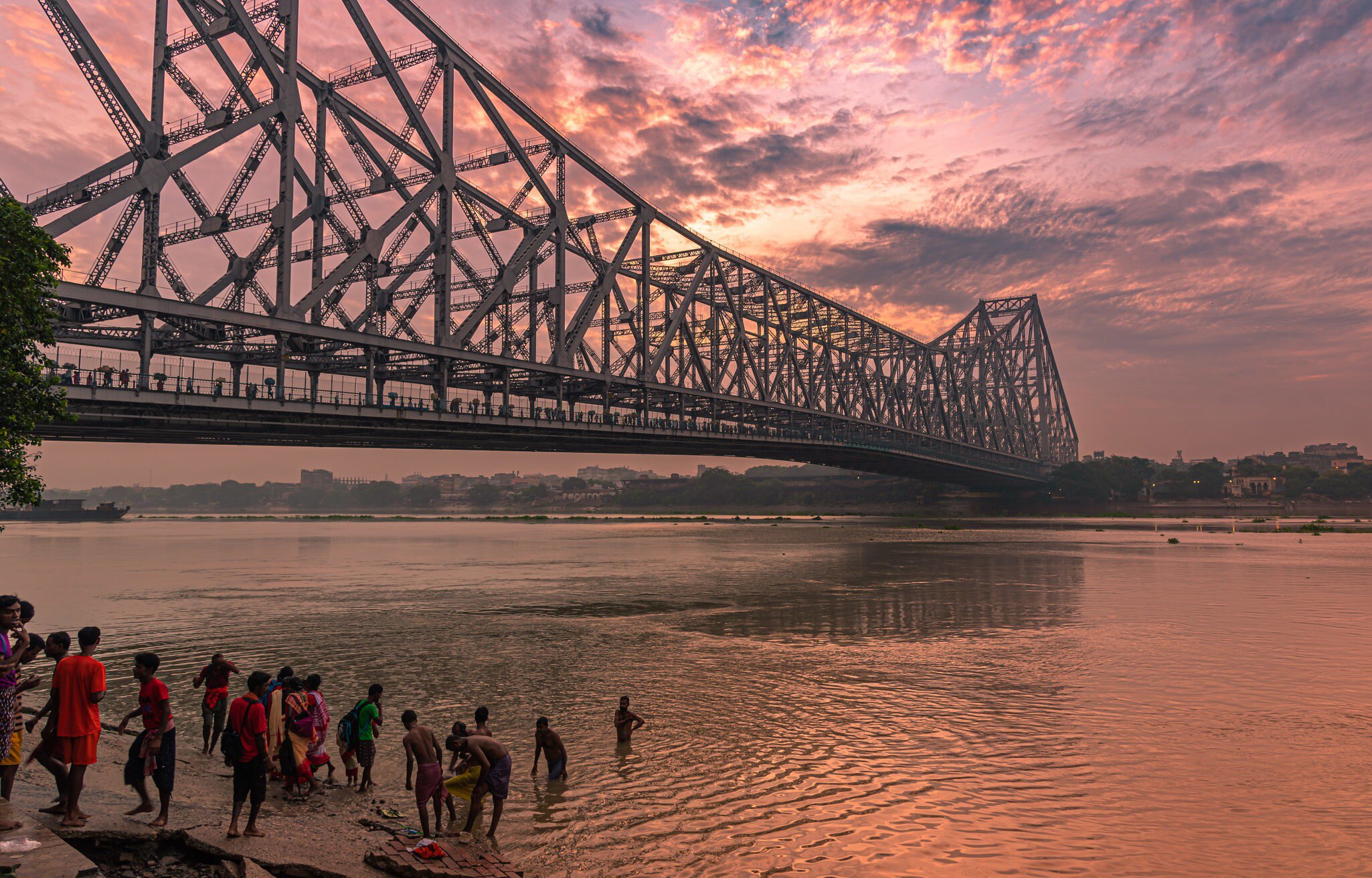 People taking a Holy bath near the Howrah Bridge, which spans the Hooghly River in West Bengal. Kolkata, India.