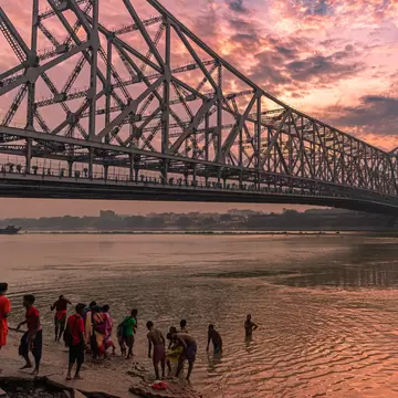 People taking a Holy bath near the Howrah Bridge, which spans the Hooghly River in West Bengal. Kolkata, India.