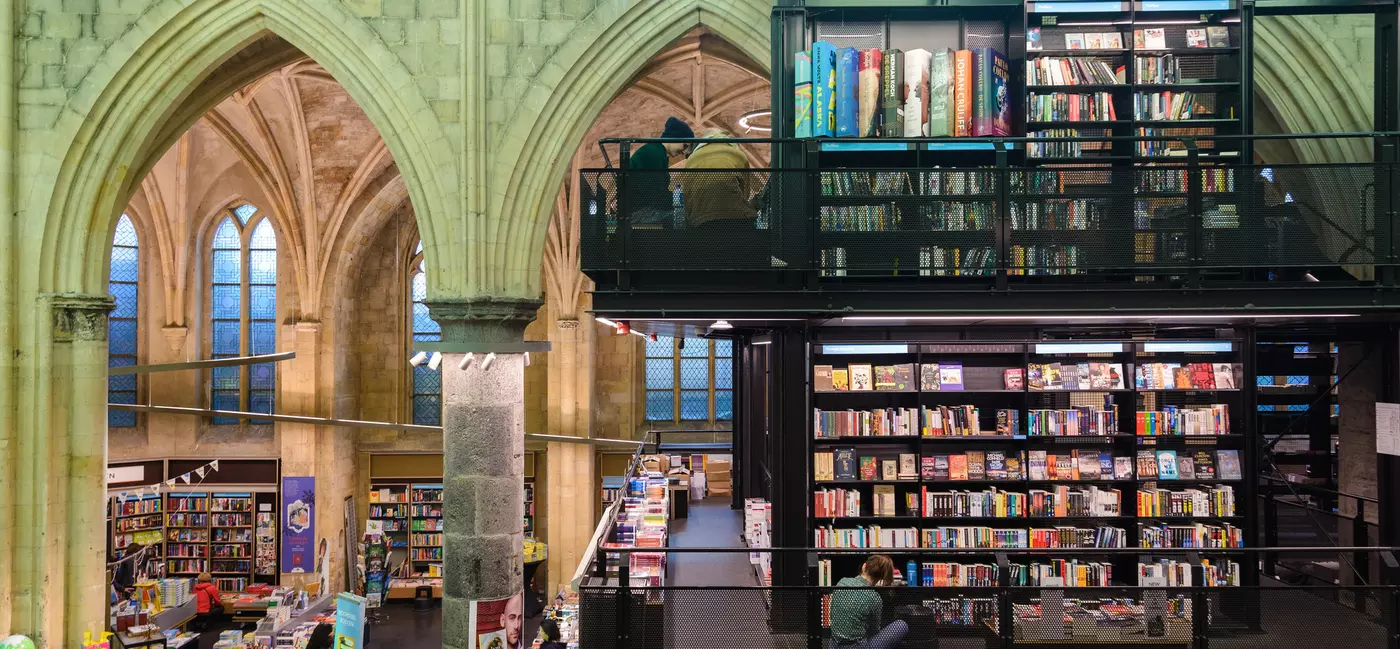 Tall stone columns and vaulted ceilings host modern black metal bookshelves in this bookstore inside a former medieval church.