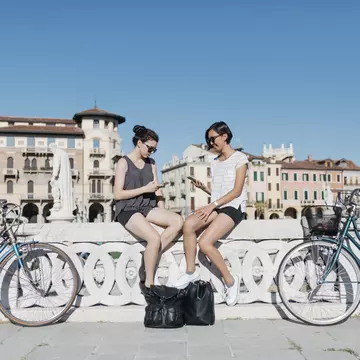 Two young tourists sitting on a bridge in Padua, Italy.jpg