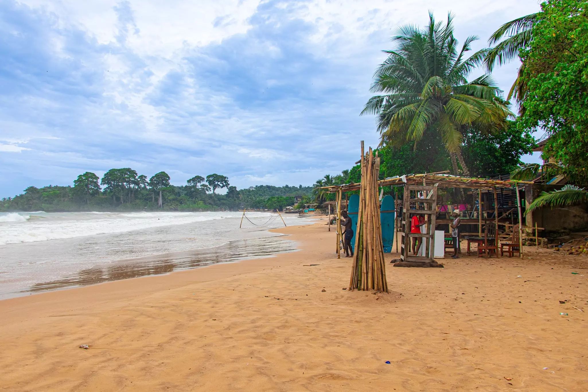 Busua Beach, with three people in a nearby hut