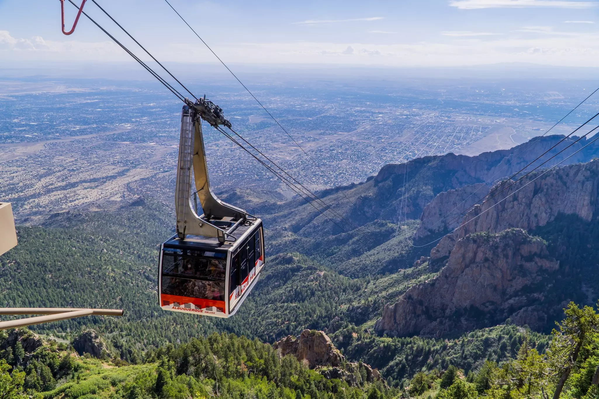 A cable car at the Sandia Peak Tramway approaching the top of Sandia Mountain, with the city of Albuquerque in the background.