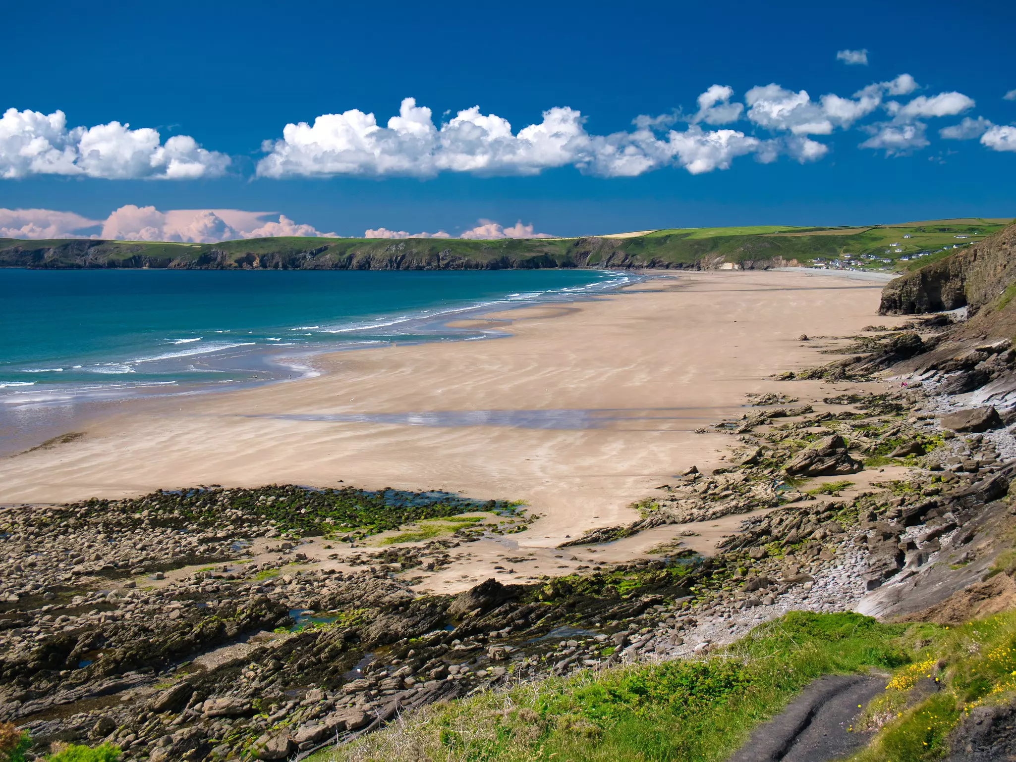 Newgale Beach in Pembrokeshire, Wales, UK, on a summer day with blue sky and clouds.