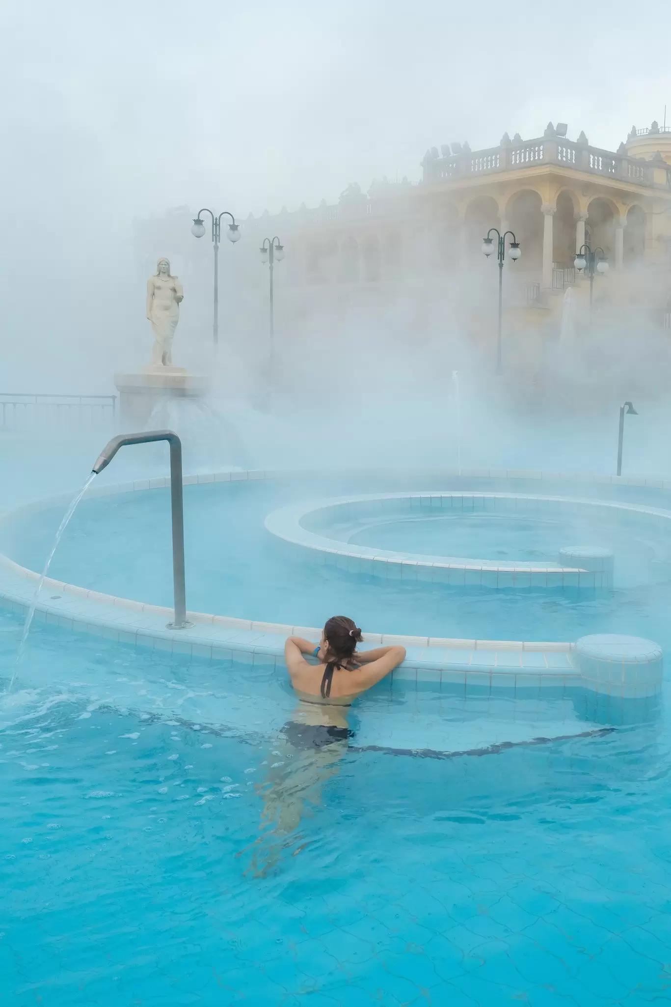 A woman relaxing at the outdoor thermal pool at Széchenyi Baths in Budapest, Hungary.