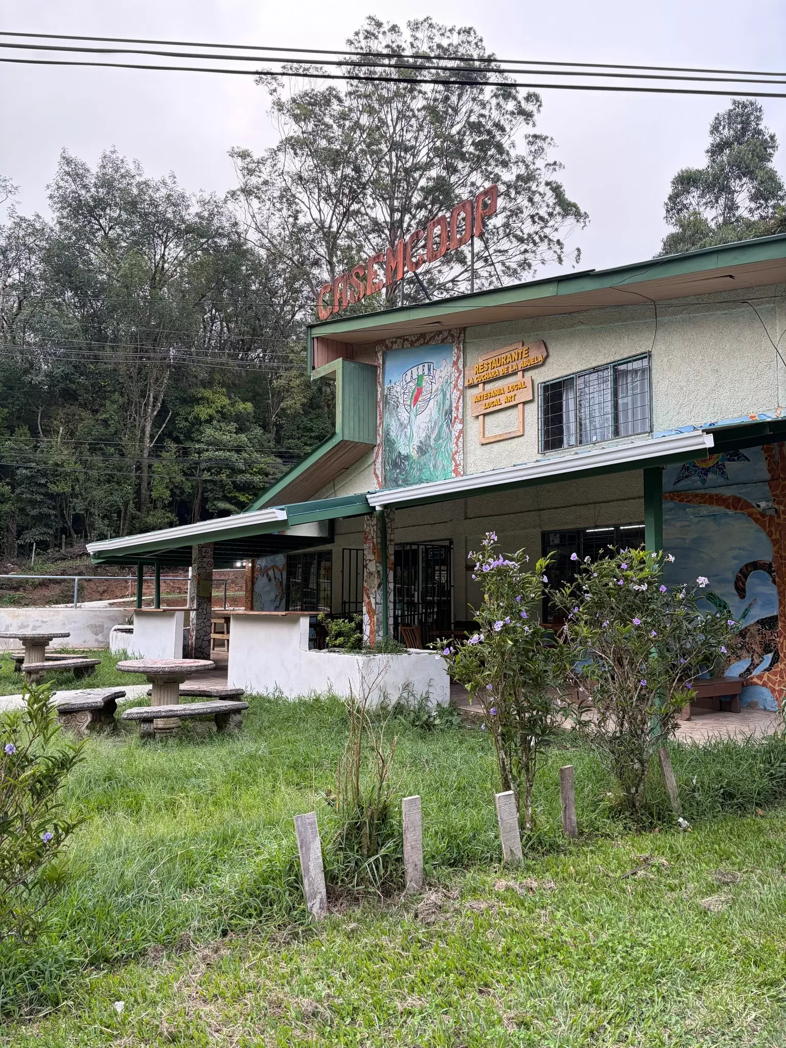 the outside of a building marked with artwork and signs on its exterior walls in the Costa Rican cloudforest