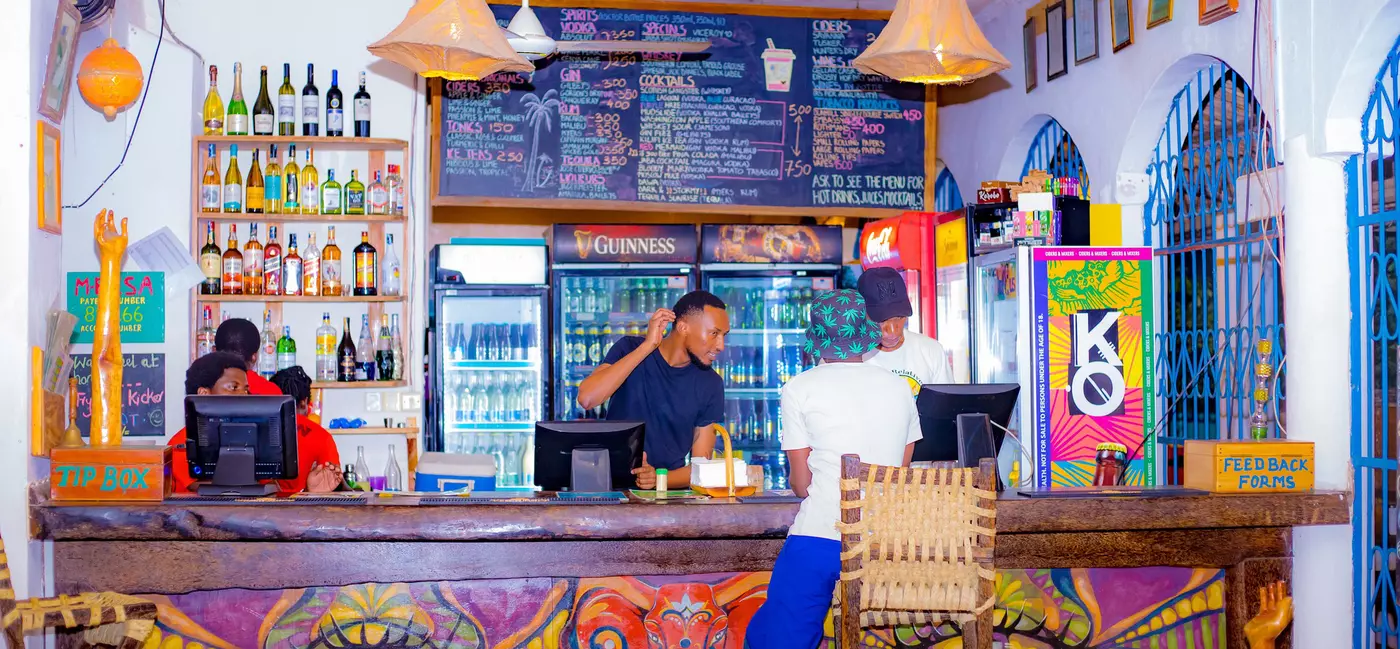 Staff behind a bar stocked with wine, beer and soft drinks
