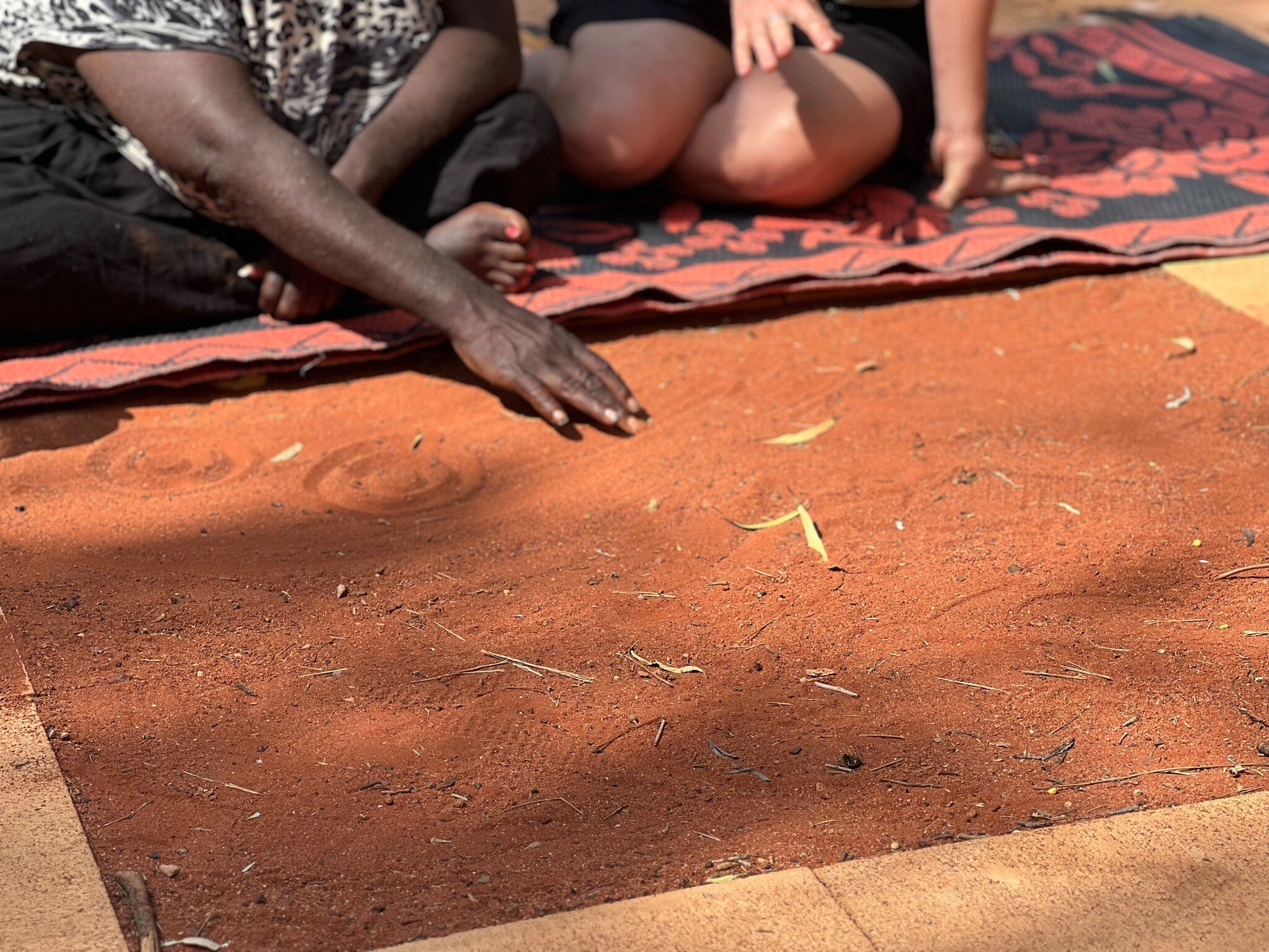 An Anangu artist from Maruku demonstrates symbology in traditional artwork at Yulara Town Square. Northern Territory, Australia.