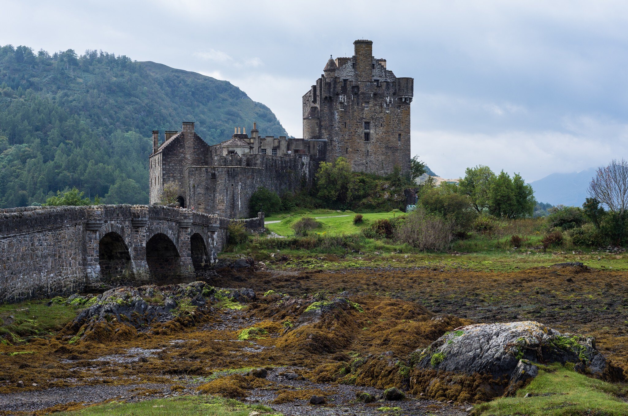 Eilean Donan Castle and its stone arched bridge in the misty Scottish Highlands