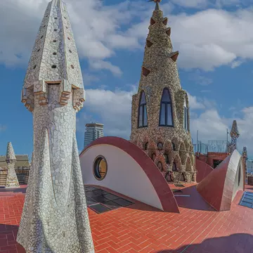 BARCELONA, SPAIN - APRIL 14, 2024: Original chimneys covered with ceramics of different colors on the roof of the Palau Guell designed by architect Antoni Gaudi. Built 1886-1888, UNESCO.
