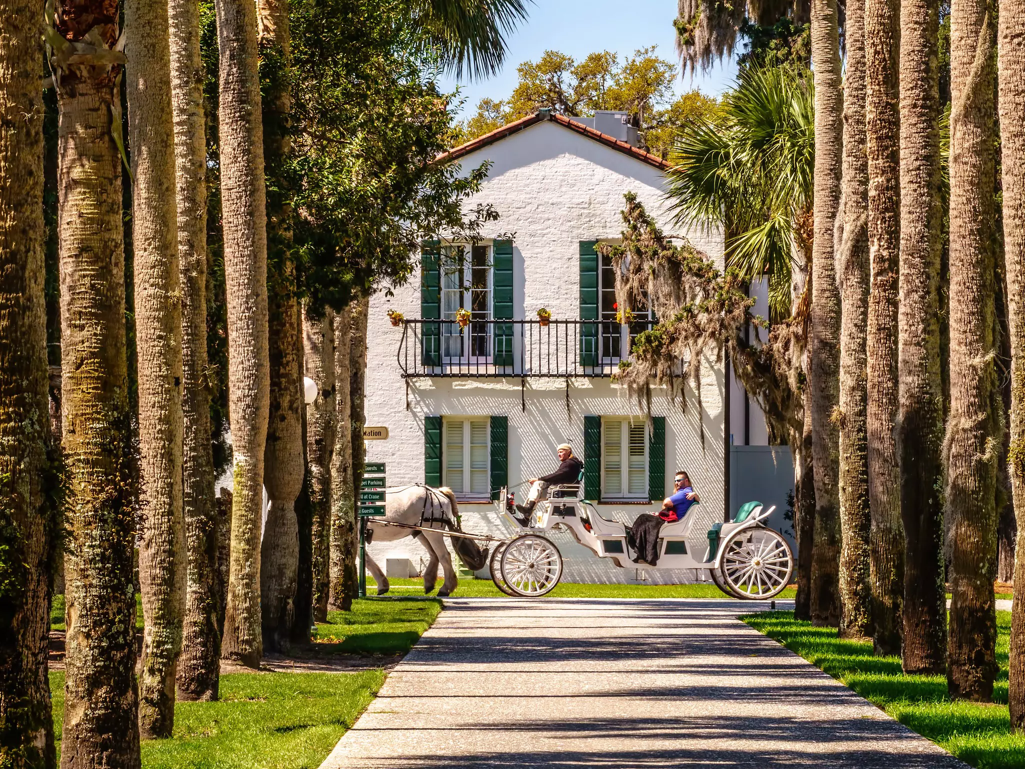 A guide takes a couple on a leisurely horse-drawn carriage tour past Crane Cottage, Jekyll Island, Georgia