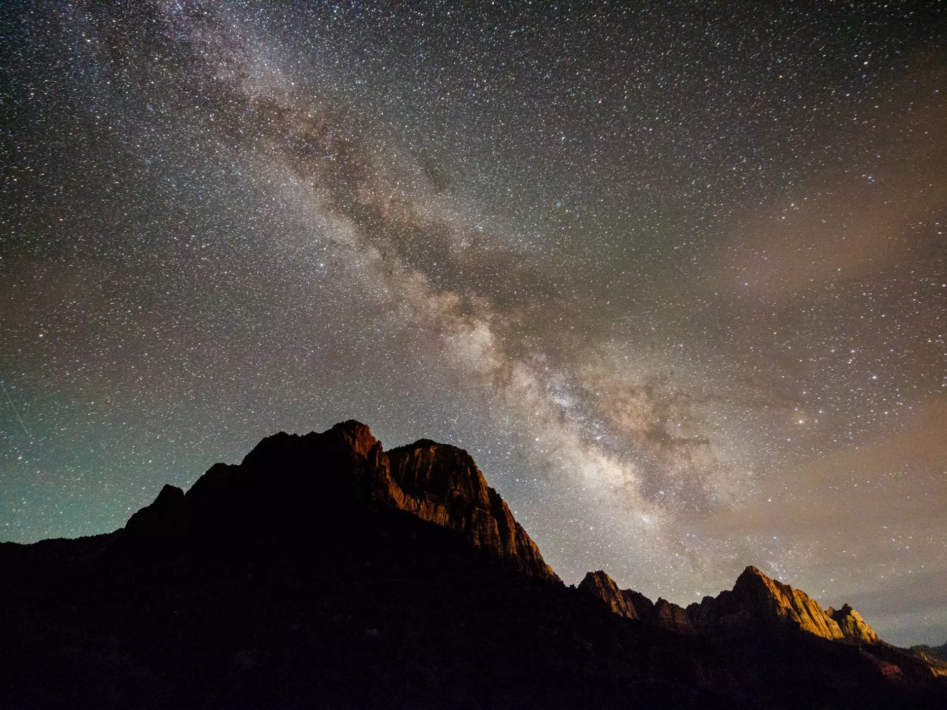 A streak of tightly packed stars -- the Milky Way -- shines over the mountainous peaks in a national park
