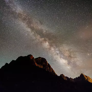 A streak of tightly packed stars -- the Milky Way -- shines over the mountainous peaks in a national park