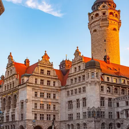 A medieval tower and ornate buildings are lit by a warm dusk light.
