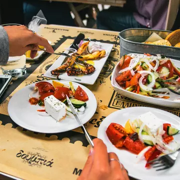 A large portion of Greek salad, grilled octopus and bread. 