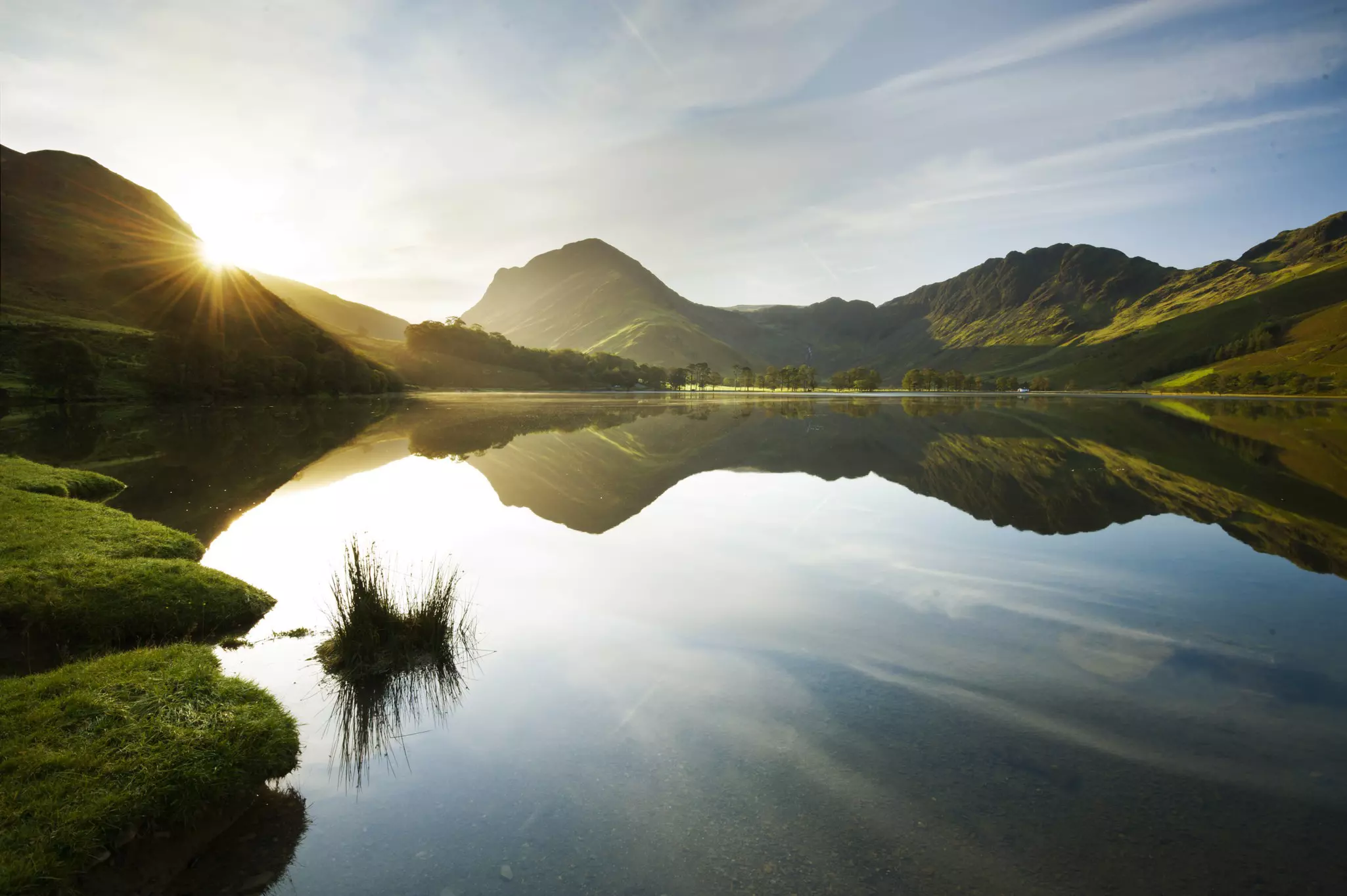 Sunlight shines over the rustic hills above a lake