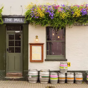 The facade of an old pub on Mill Place in Cambridge, with flowers and barrels outside