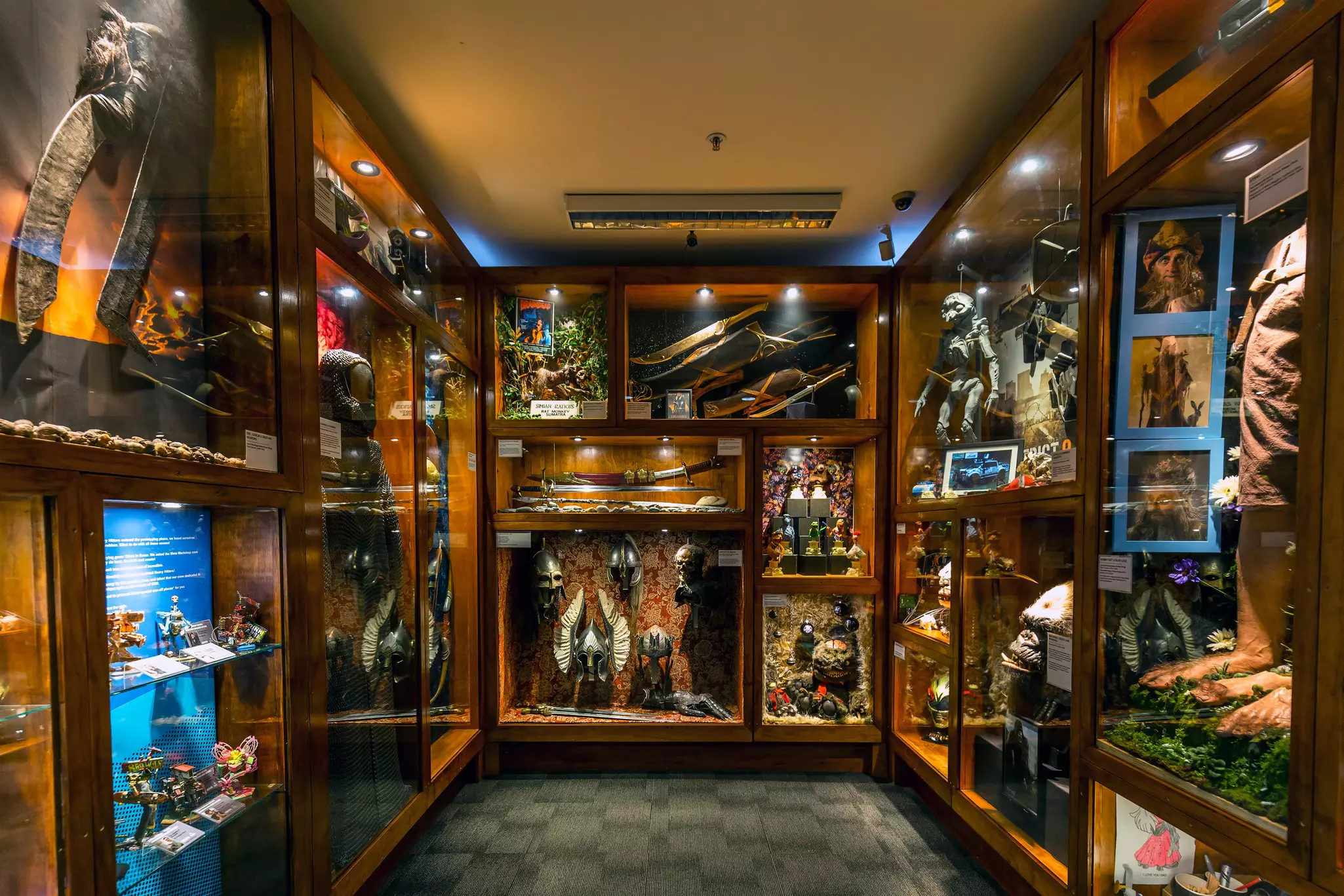 A series of glass cabinets full of props, masks and weapons used in filming and on movie sets.