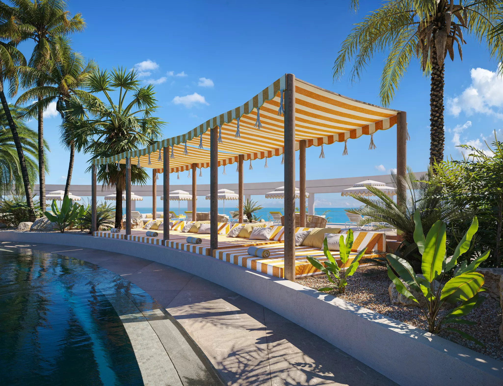 View of the pool, with canopy beds, palm trees and sea in the background at hotel Iberostar Selection, Fuerteventura