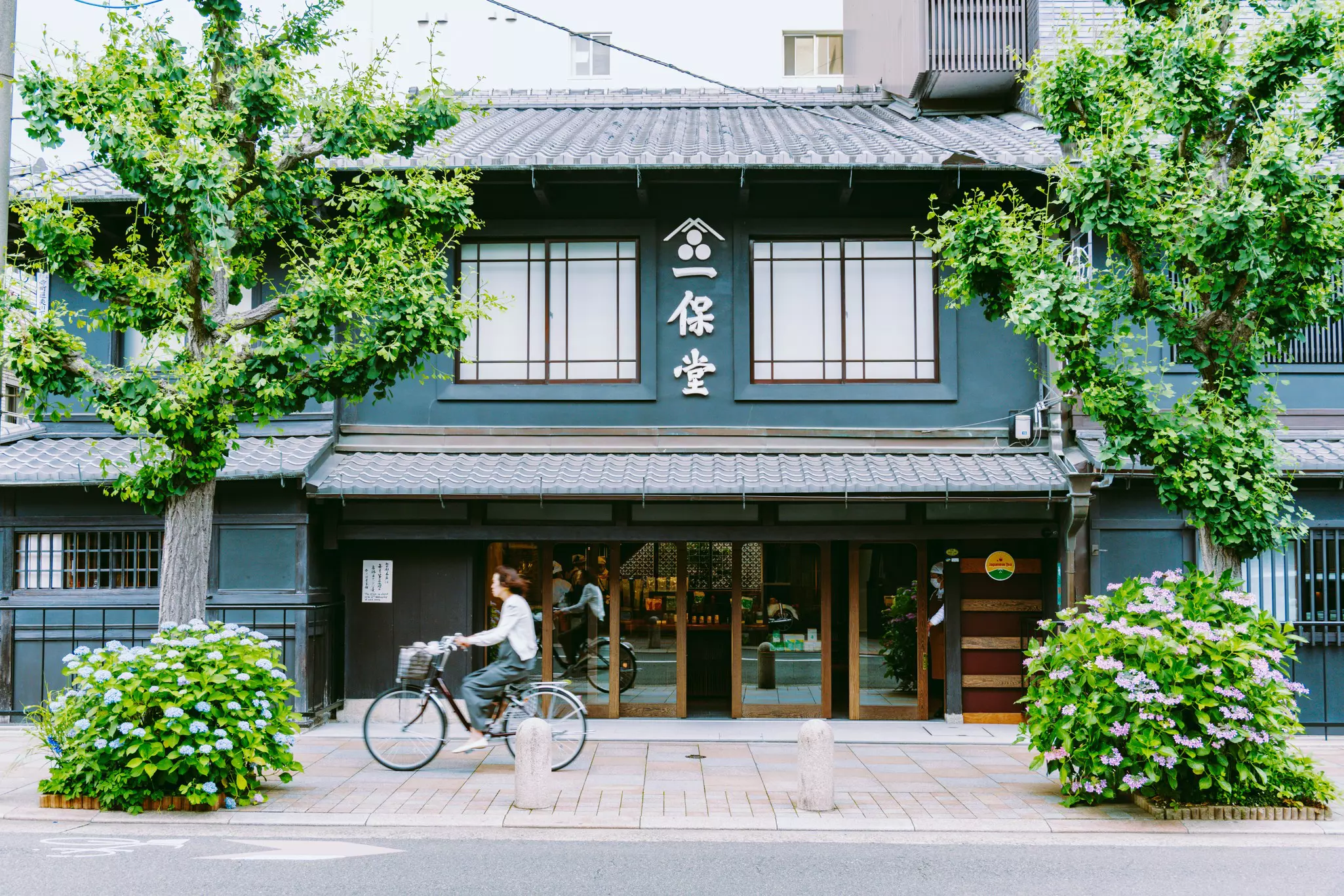 A woman on a bicycle in front of a teahouse in Kyoto