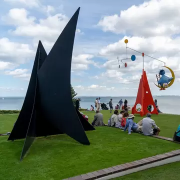 People sitting at Louisiana Museum of Modern Art, which brings together green spaces, architecture and art. Copenhagen, Denmark.