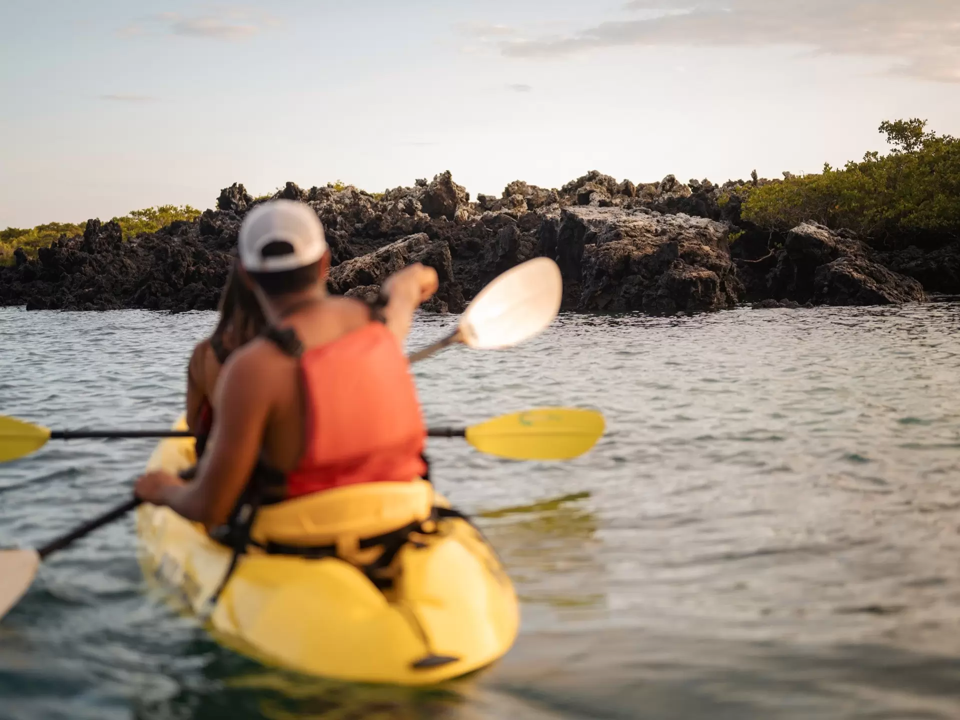 Two people wearing life vests are kayaking during sunset on the ocean in Galapagos Islands in Ecuador 
