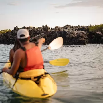 Two people wearing life vests are kayaking during sunset on the ocean in Galapagos Islands in Ecuador 