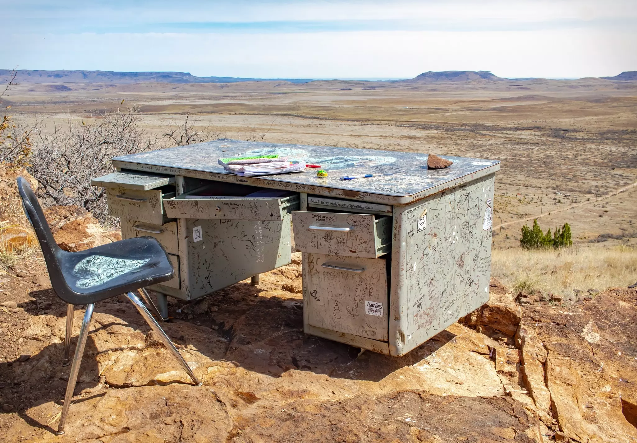 A desk and chair covered in graffiti in front of a large desert.