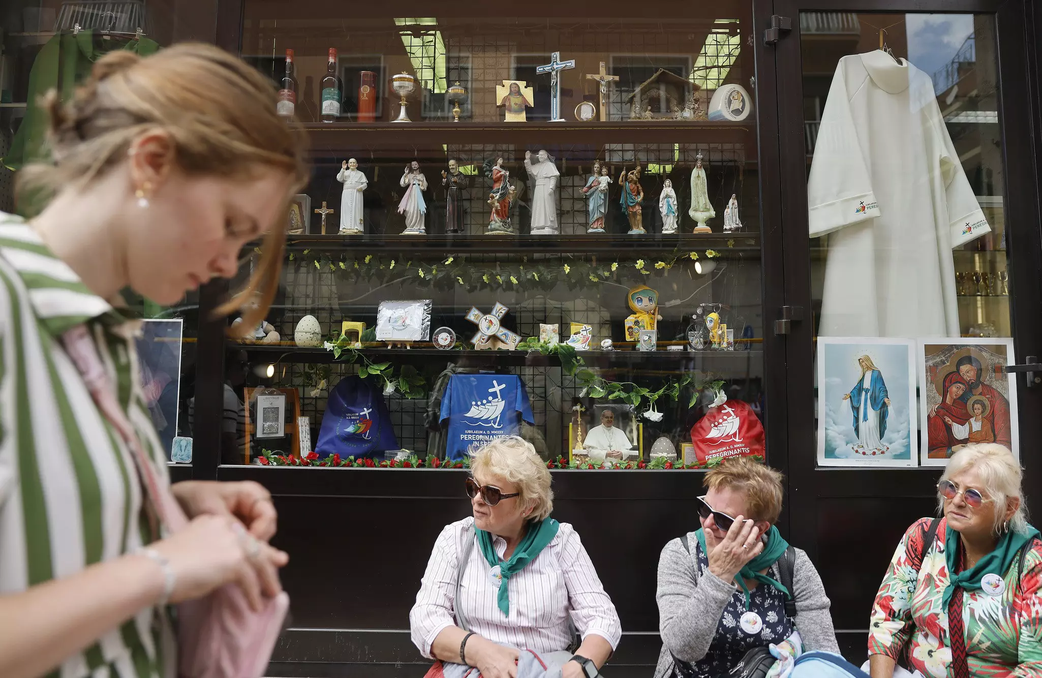 Women sit outside a store selling religious items near the Vatican