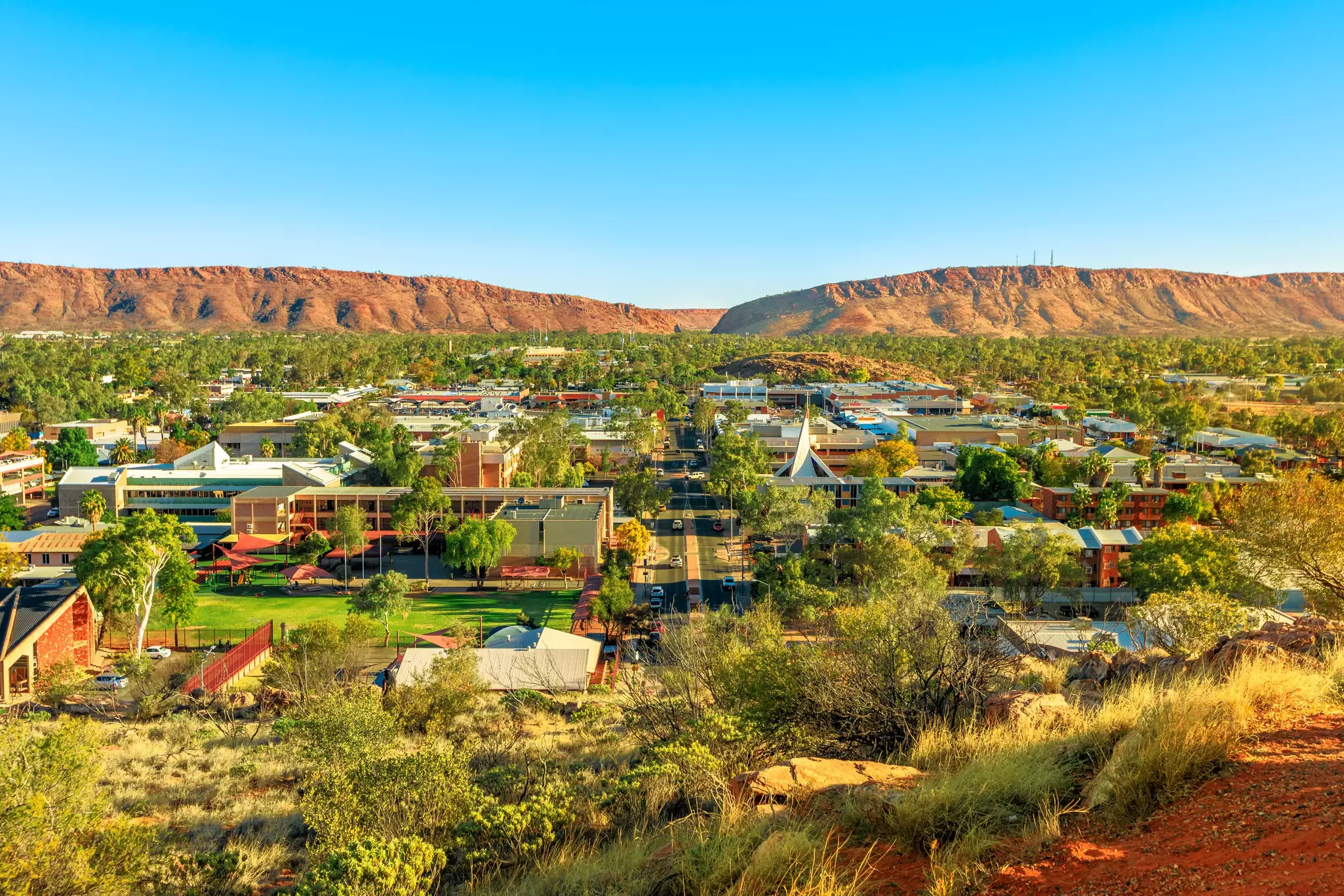 Aerial view of Alice Springs skyline in Australia from Anzac Hill Memorial lookout with main buildings of Alice Springs city downtown. Red Centre desert with Macdonnell ranges of Northern Territory. 