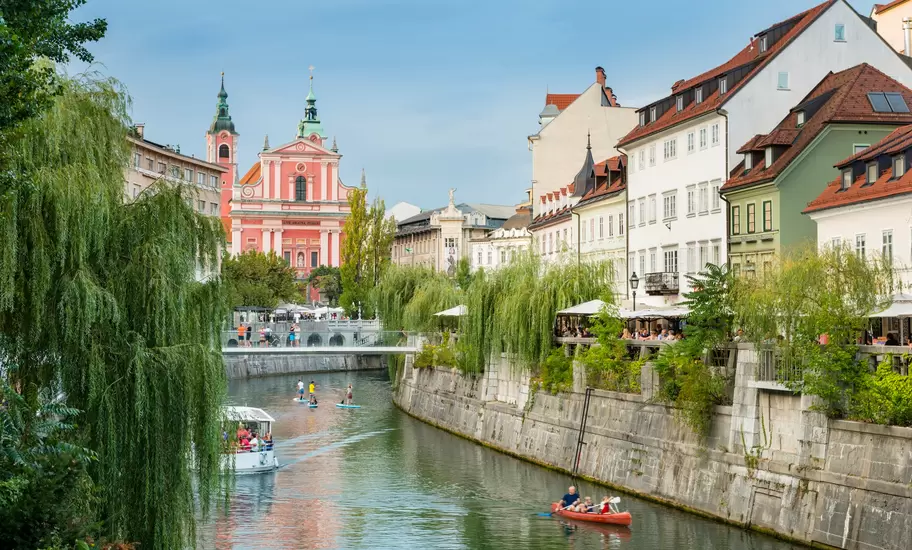 KayakBoats and paddle boarders travel down the tree-lined Ljubljanica River, which flows through the centre of Ljubljana.