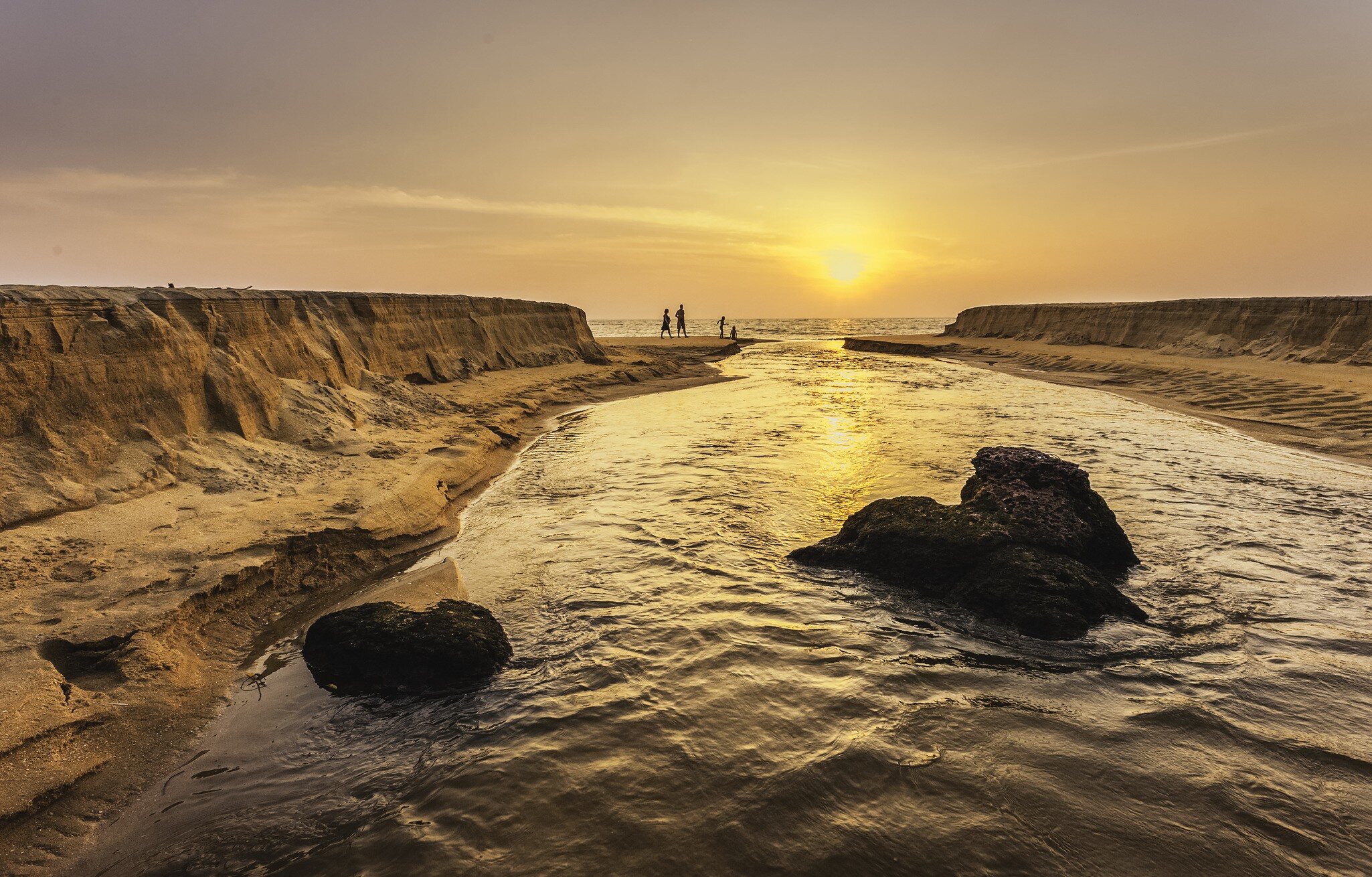 Kannur, Kerala, India. Sunset as Thottada river carves a channel through the sandy beach at Thottada village and spills into Arabian Sea, north Kerala, India.
