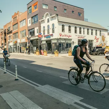 Cyclists on a quiet Chicago street that's lined with restaurants and vintage stores.