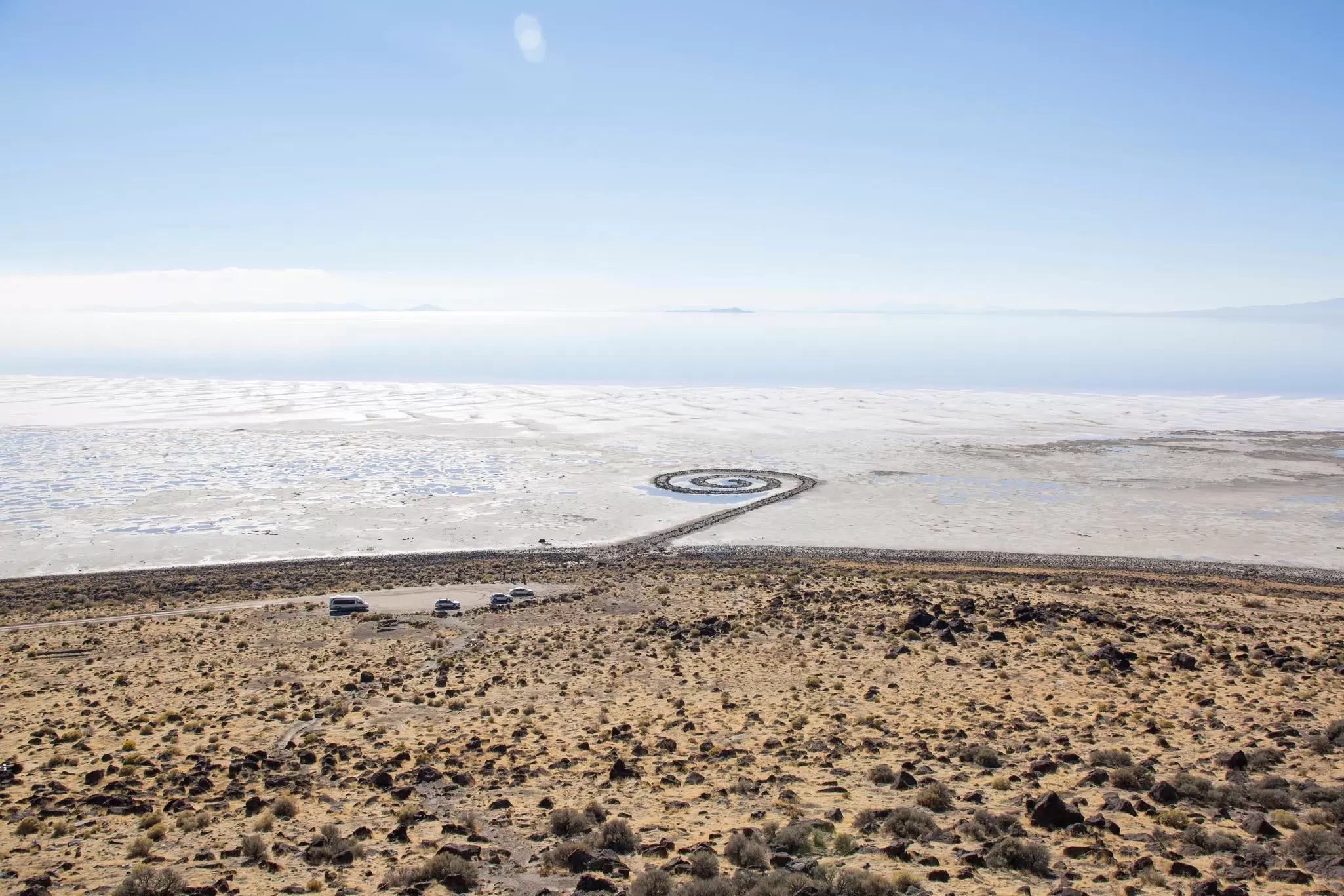 Robert Smithson's Spiral Jetty land artwork coiling into the Great Salt Lake, with cars parked nearby